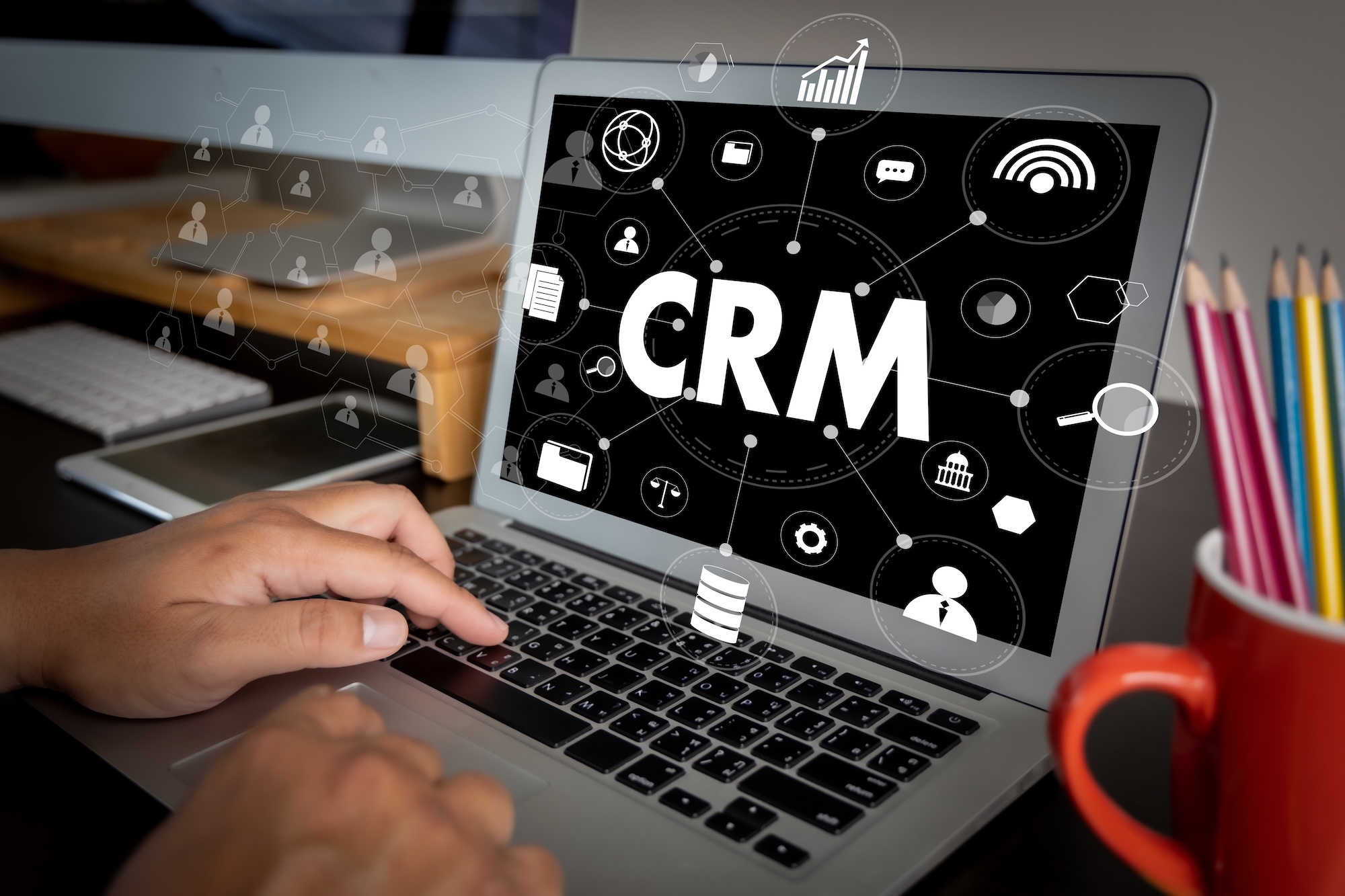 CRM software interface displayed on a laptop with customer data, analytics, and business management icons.